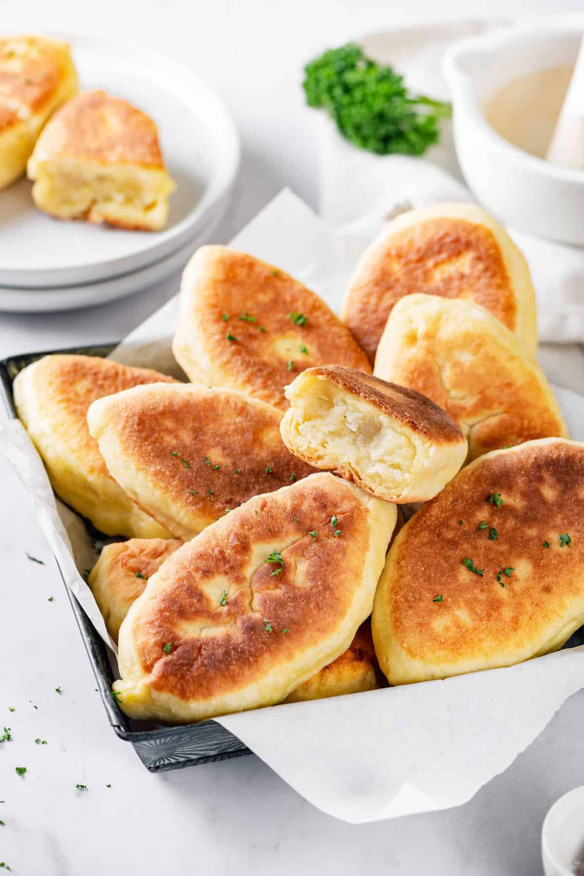 A close-up view of a tray full of easy piroshki or pirozhki with mashed potato filling.