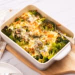 An image of broccoli cheese casserole served on a table with a spoon on the right side.