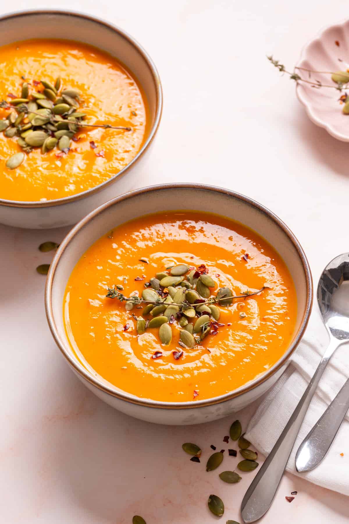 An image of acorn squash soup in a bowl garnished with thyme.