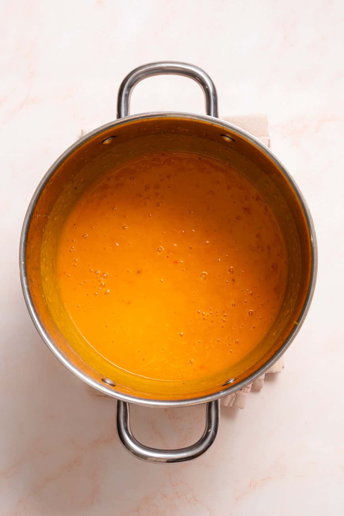 An image of acorn squash soup being being blended smoothly with an immersion blender.