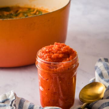 Close up image of the pepper sauce in a jar, with an orange Dutch oven in the background