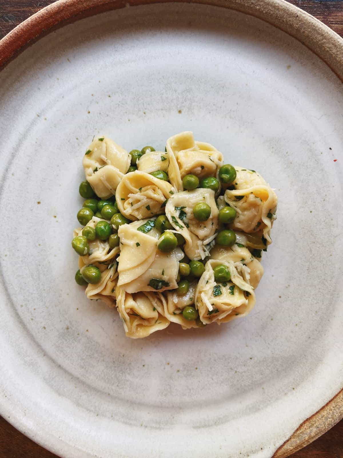 Overhead view of tortellini and green pea salad placed on a plate.