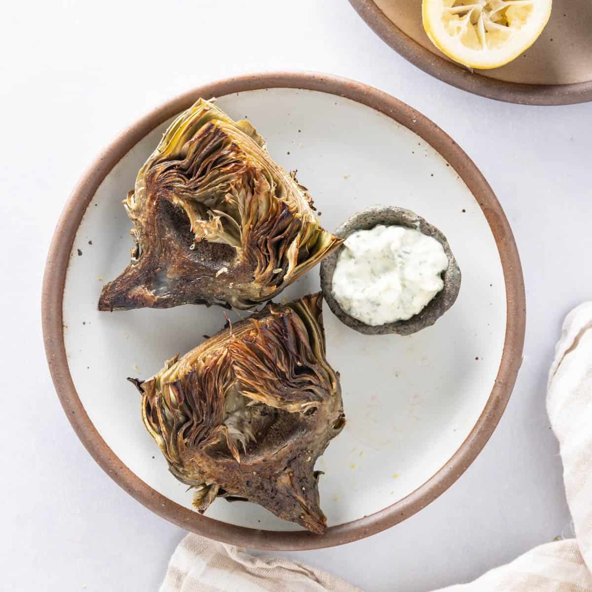Close up of air fryer artichokes on a plate with basil aioli