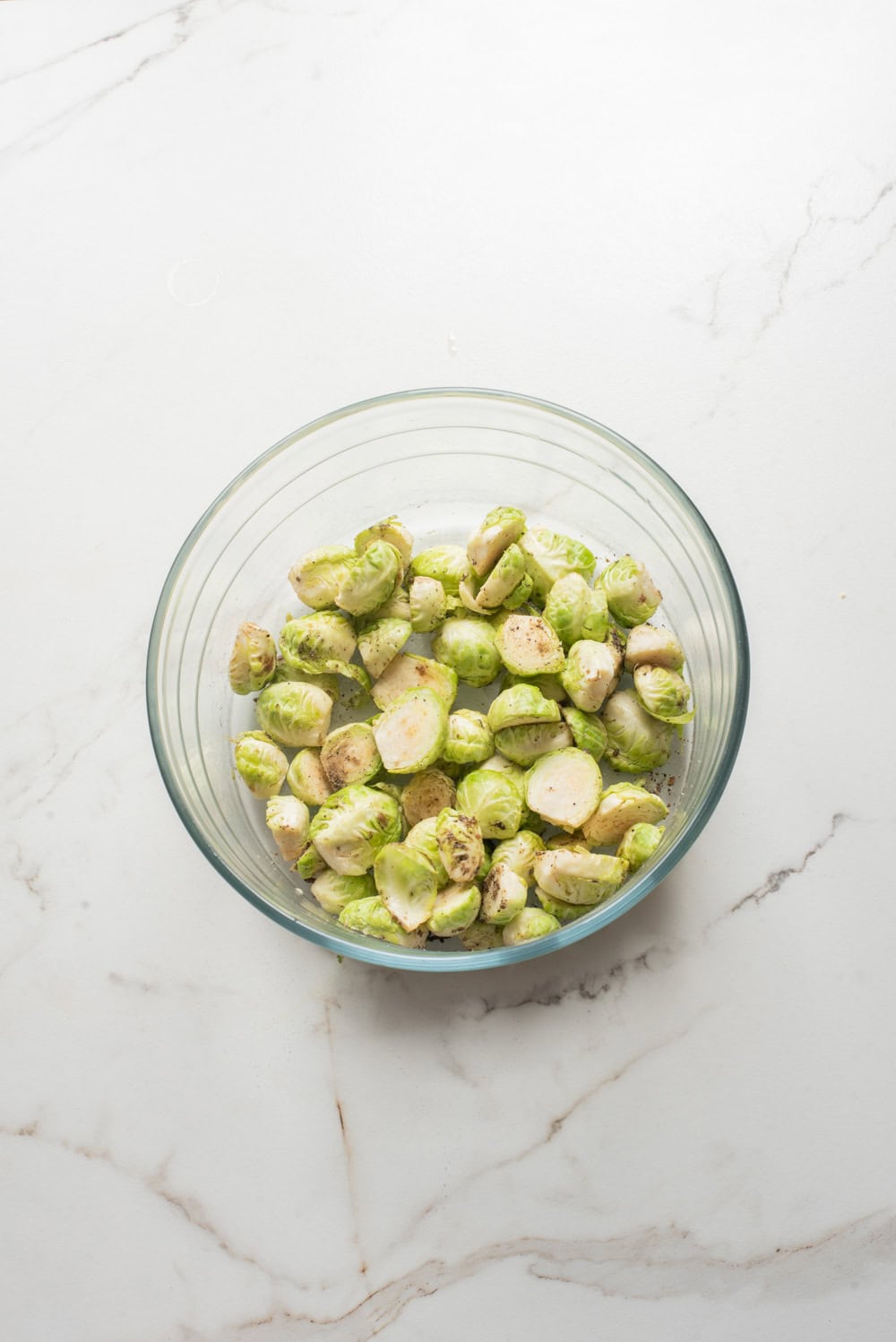 Overhead image of Brussels sprouts tossed with oil and seasonings before air frying.