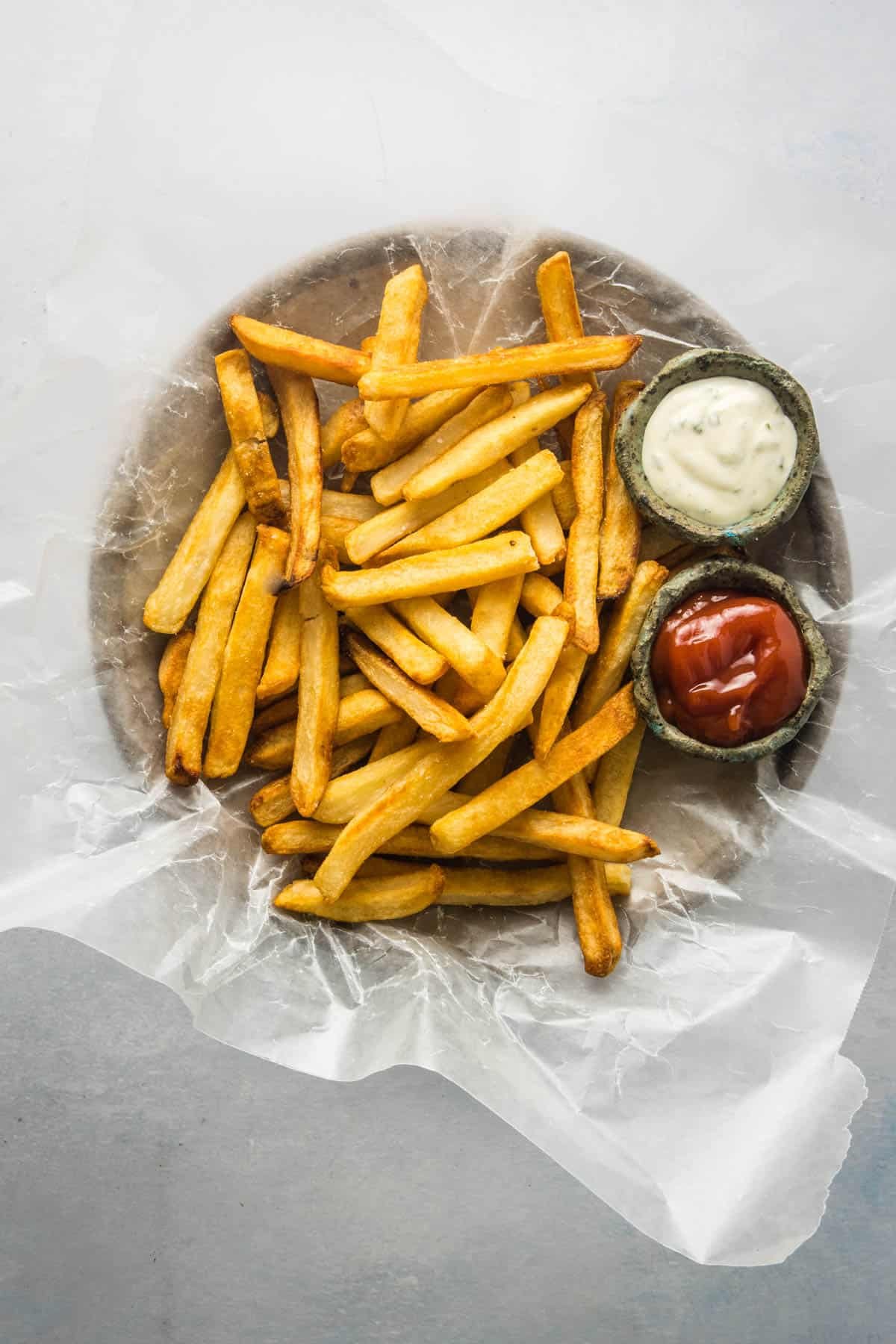 Close up of air fryer French fries on a plate with ketchup and ranch dipping sauces