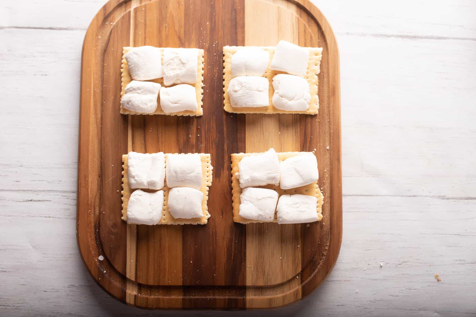 Overhead view of marshmallows cut in half and placed above the wooden board.