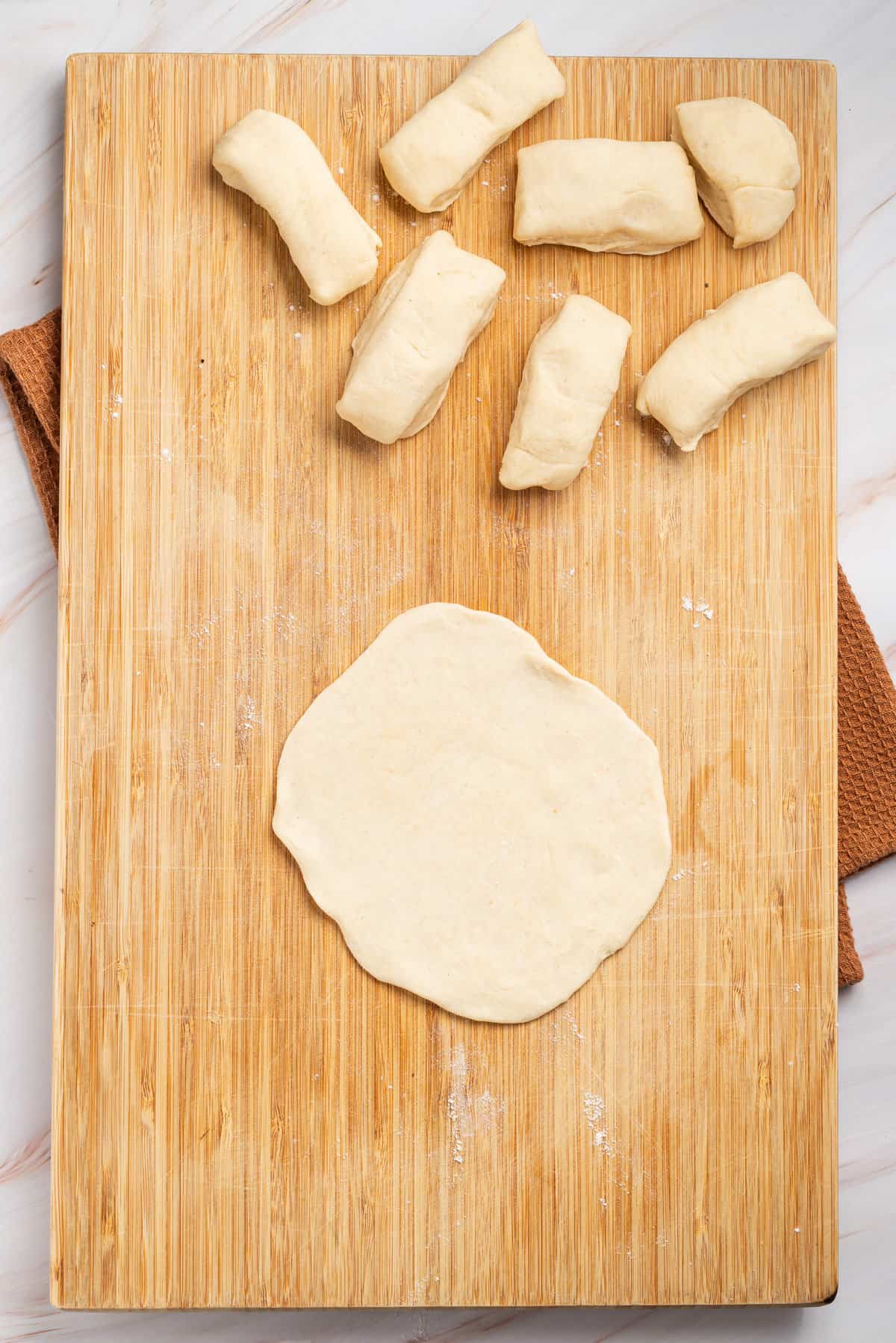 An image of samosa dough being flattened on a board.