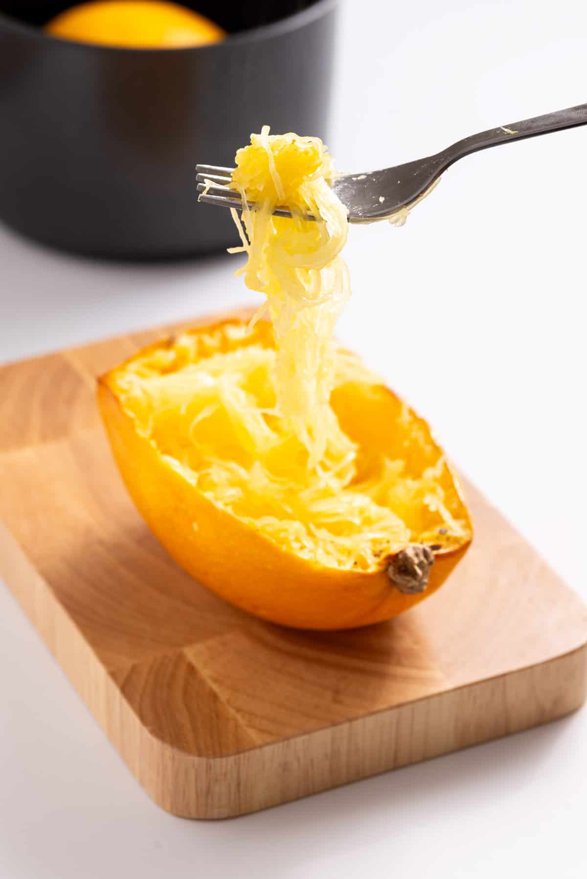 An image of a fork raising up a few strands from the spaghetti squash.