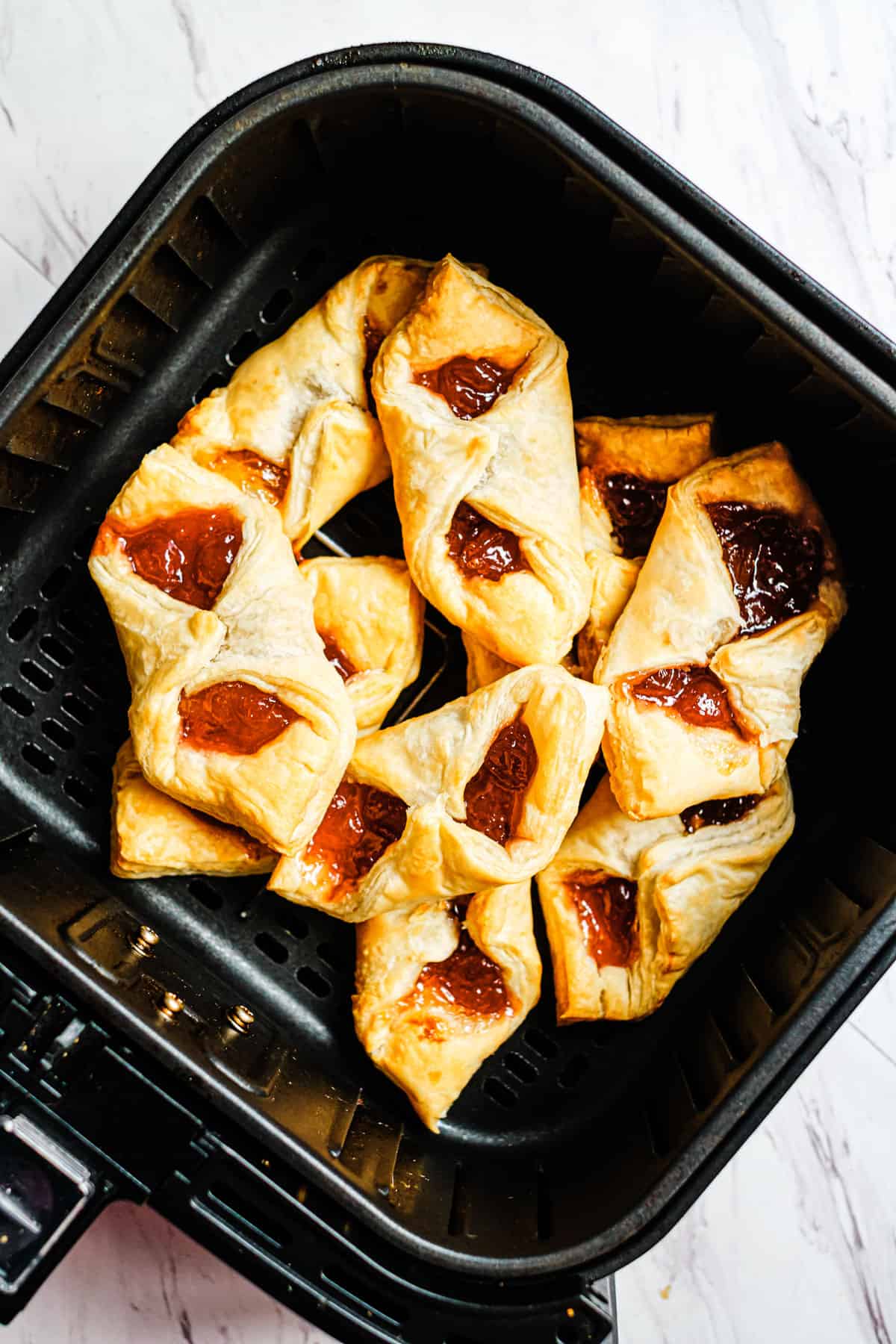 An overhead view of cooked air-fried puff pastry breakfast bites placed in the air fryer basket.