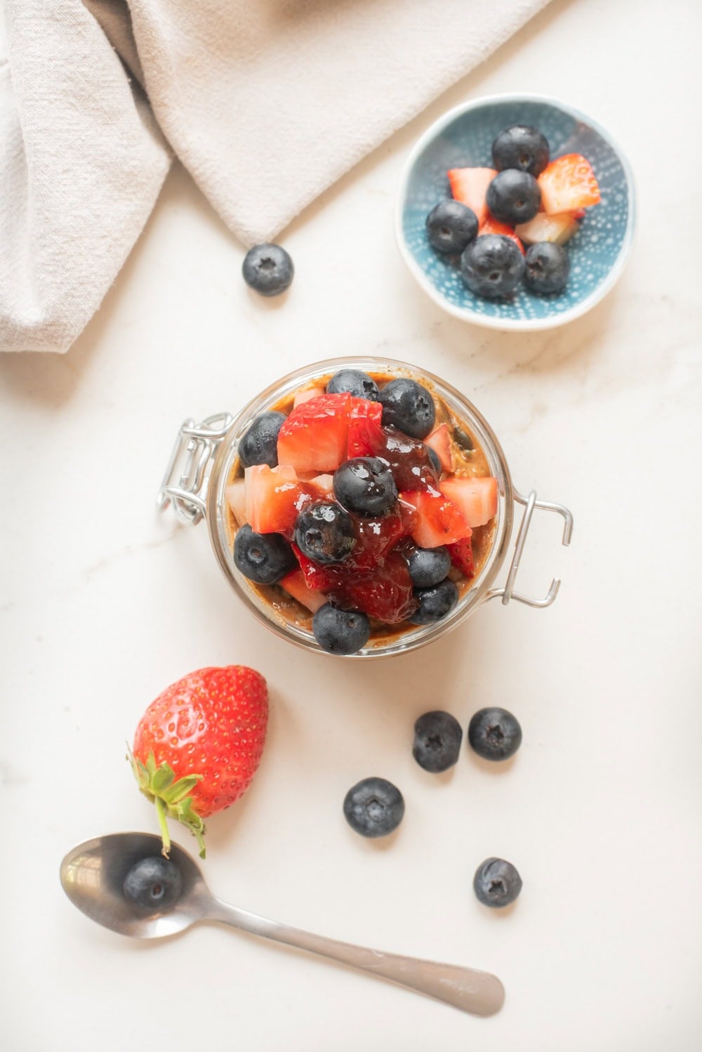 Almond butter and jam overnight oats with toppings in a jar.