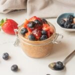 Close-up of almond butter and jam overnight oats with toppings in a jar.