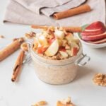 Close-up image of apple pie chia overnight oats with toppings in a jar.
