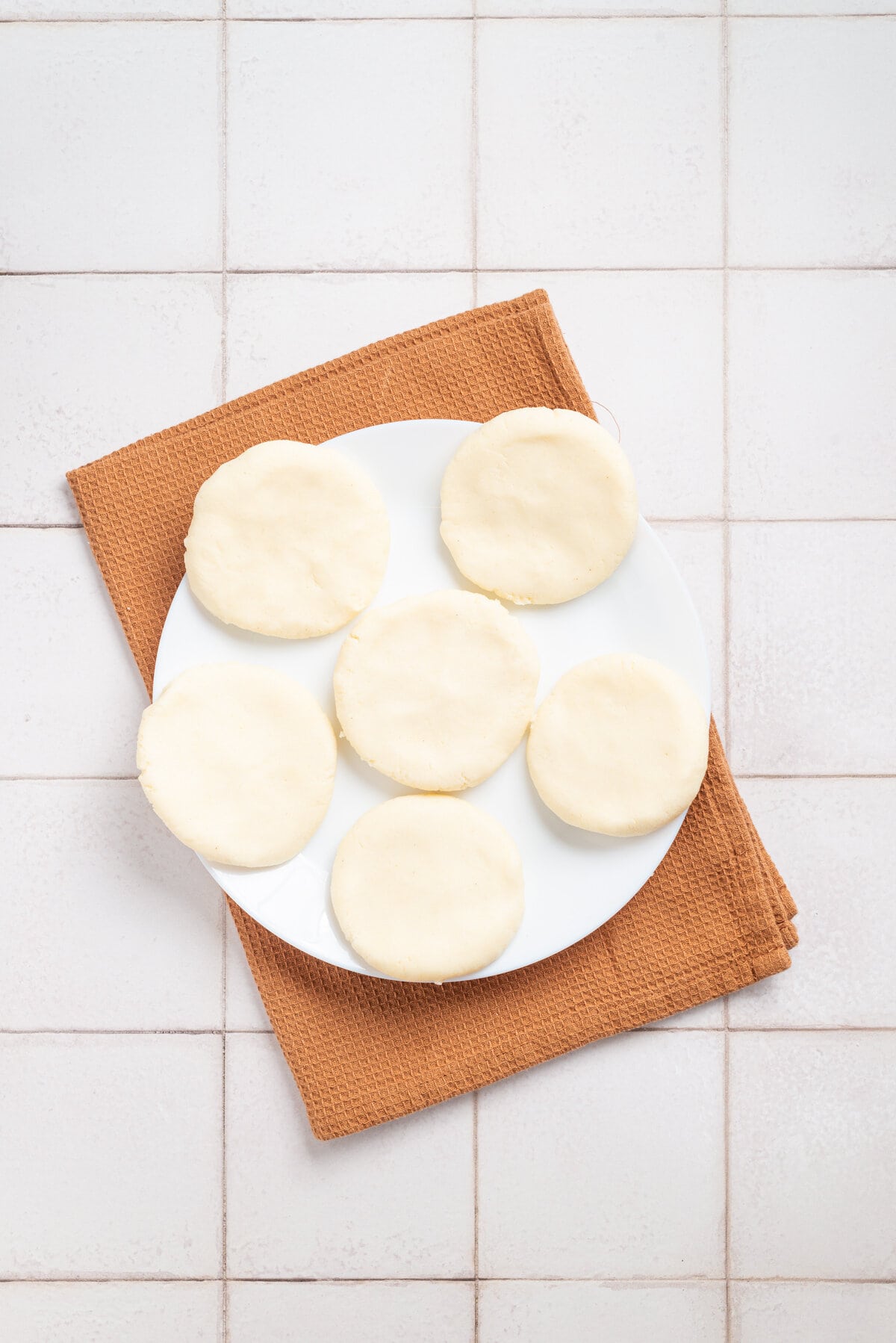 An overhead image of each dough flattened into round discs on a plate.