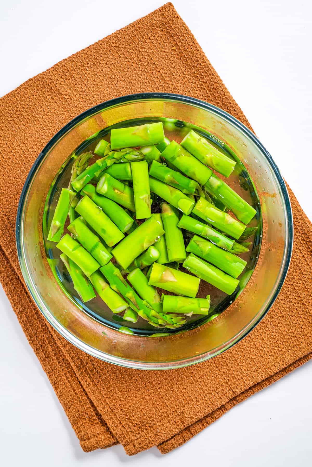 Overhead view of boiled asparagus in a glass bowl.