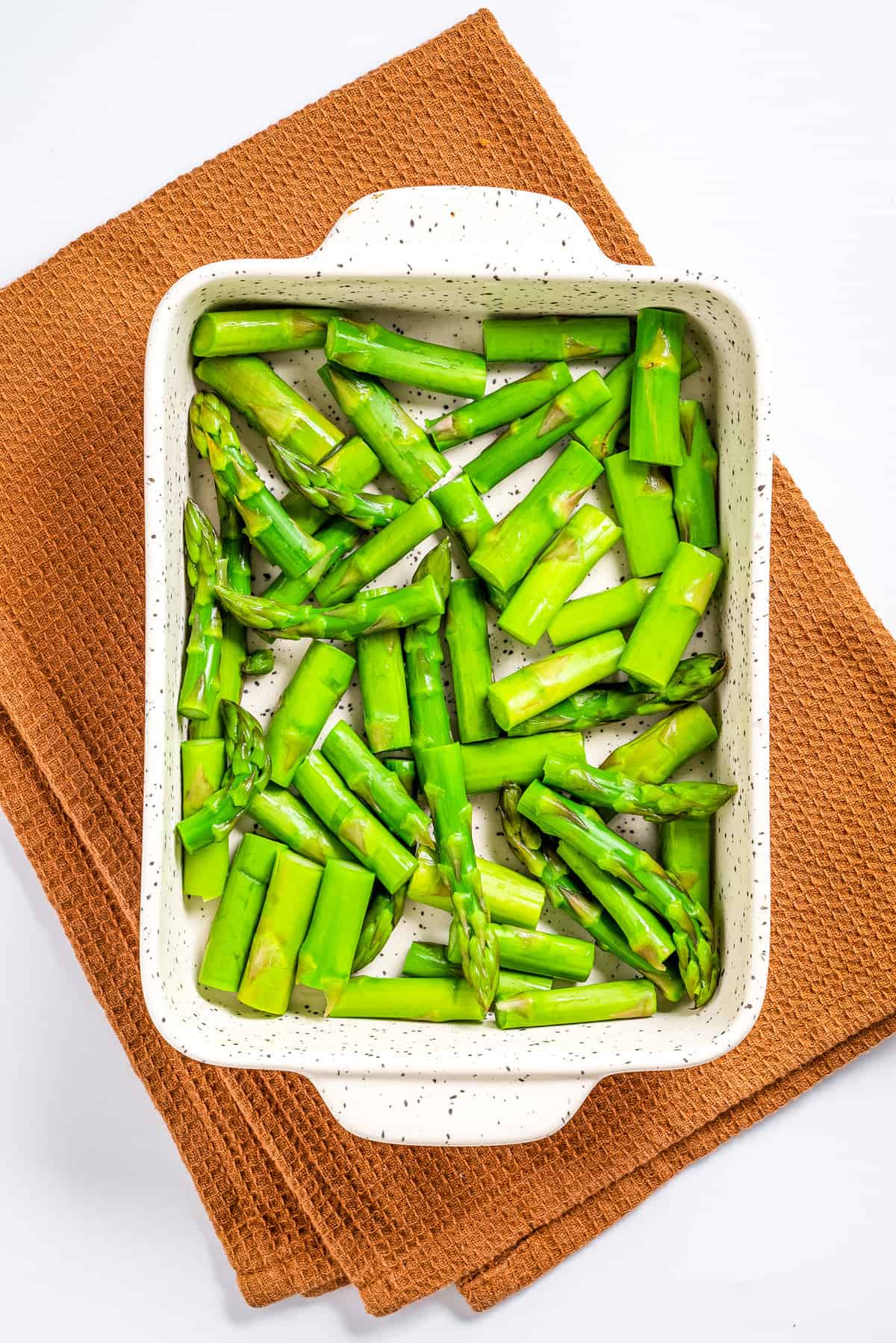Overhead view of cooked asparagus placed in a baking dish.