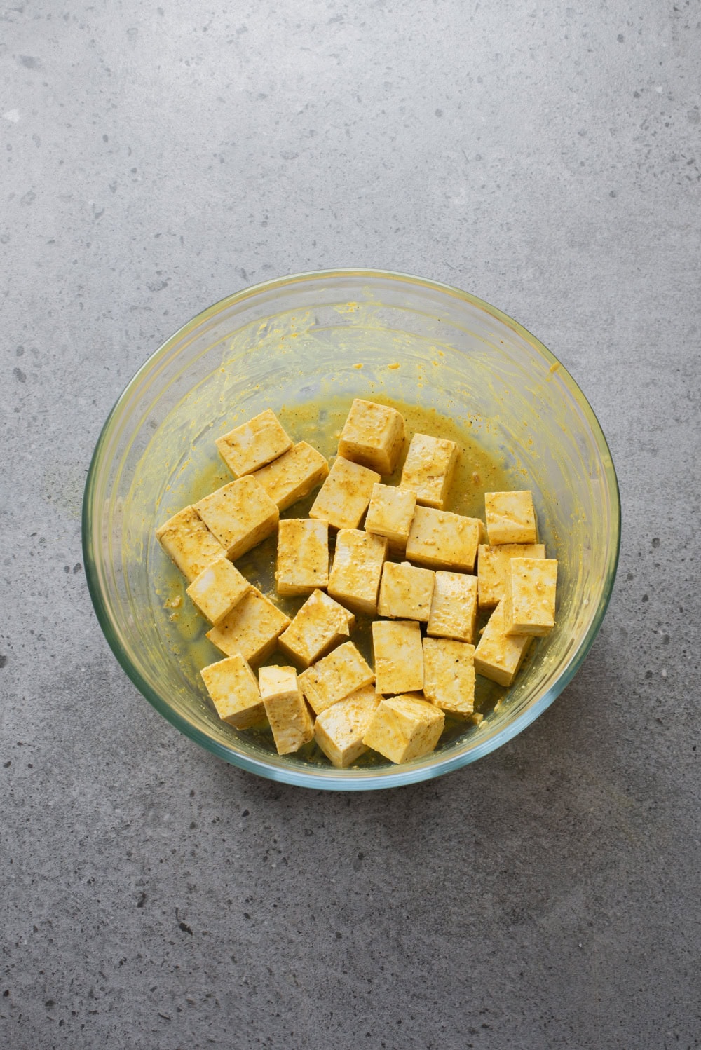 An overhead image of the tofu cubes marinated in a bowl.