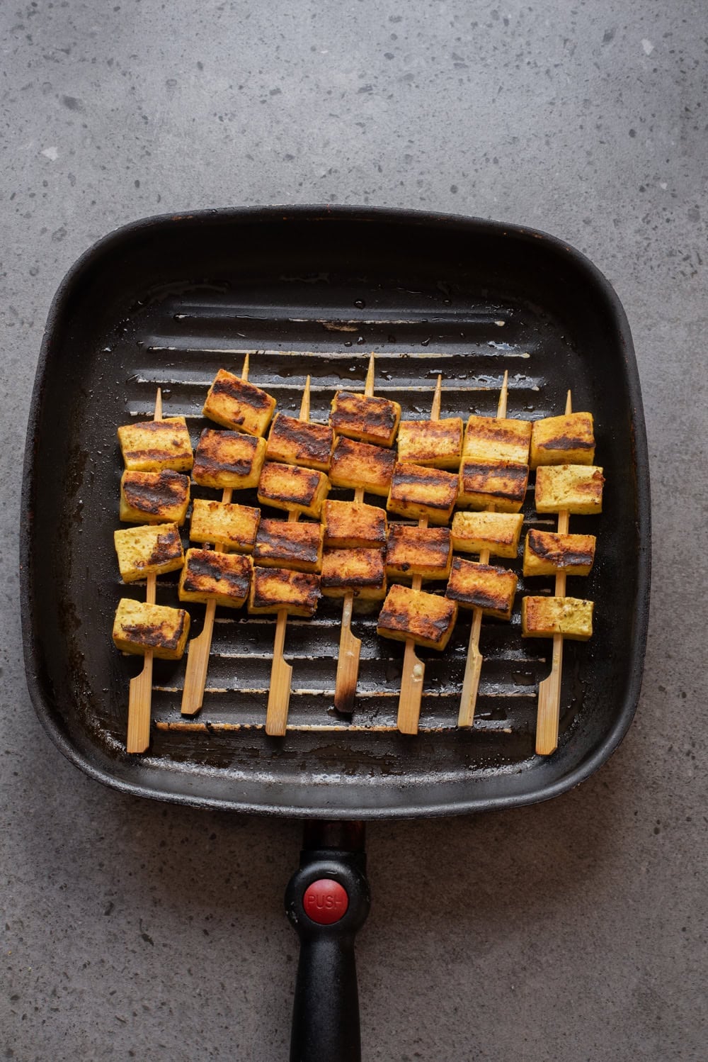An overhead image of flipping the skewers to the other side on a grill pan.