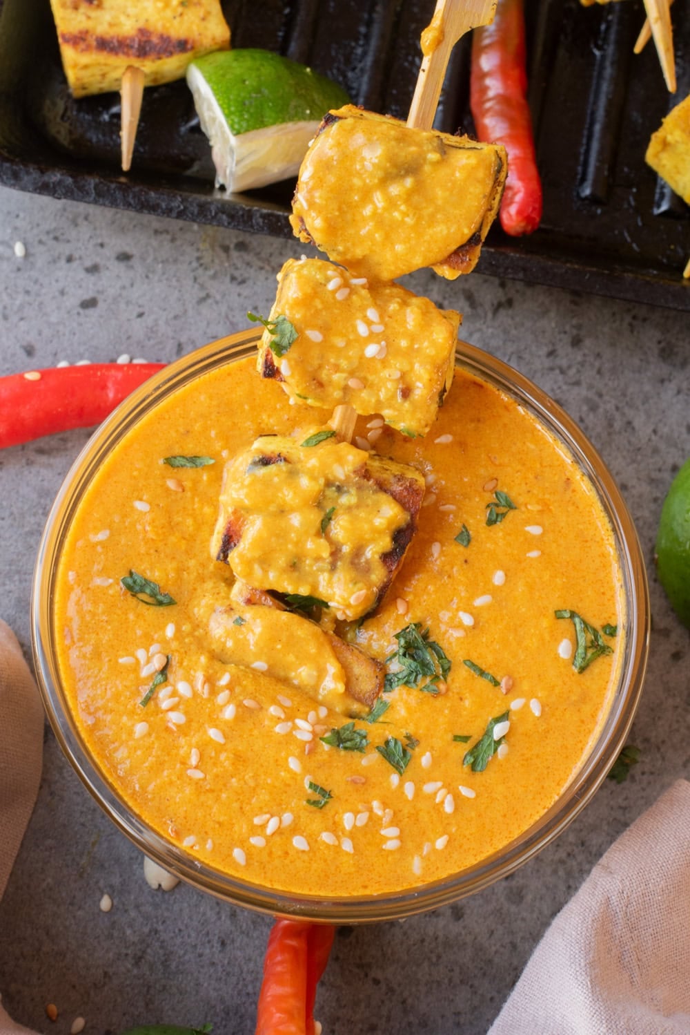 A close up image of dipping the satay to the peanut sauce.