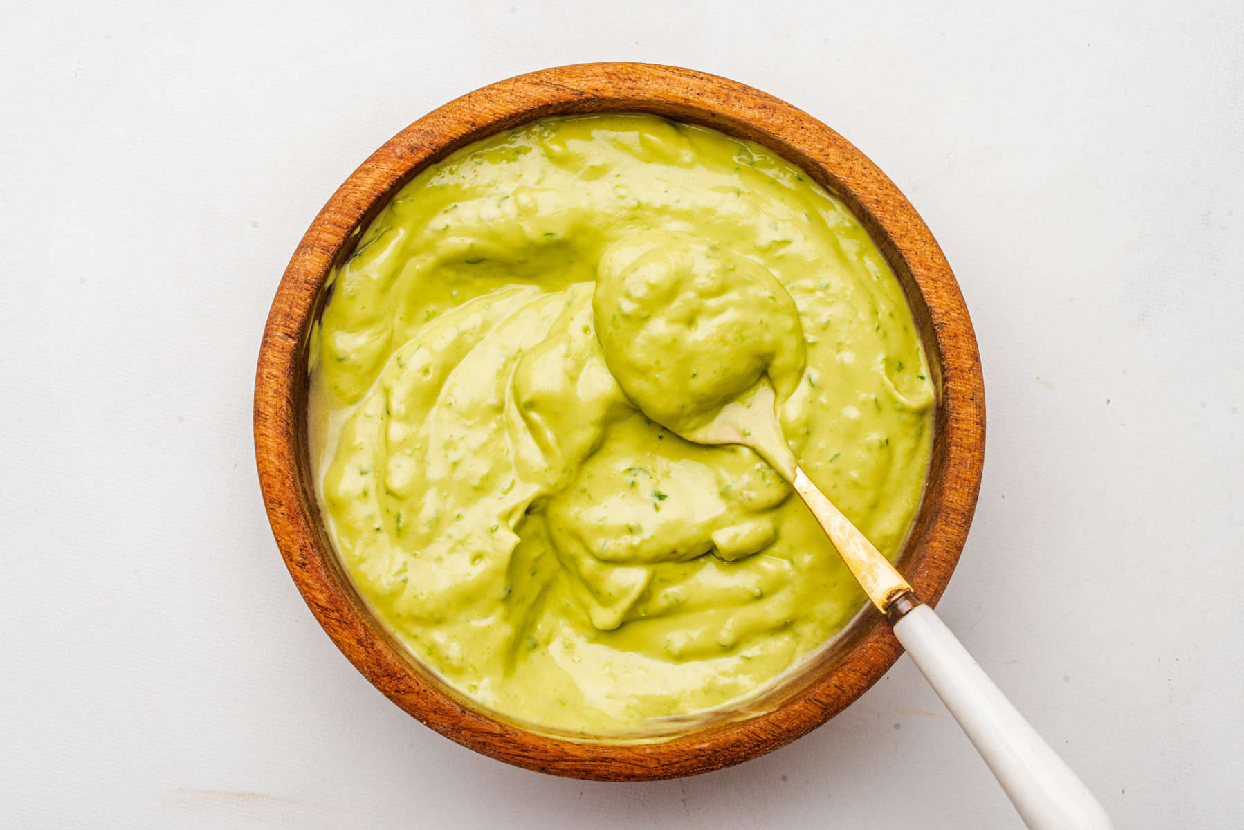 An overhead image of avocado cilantro lime dressing in a bowl with a spoon.