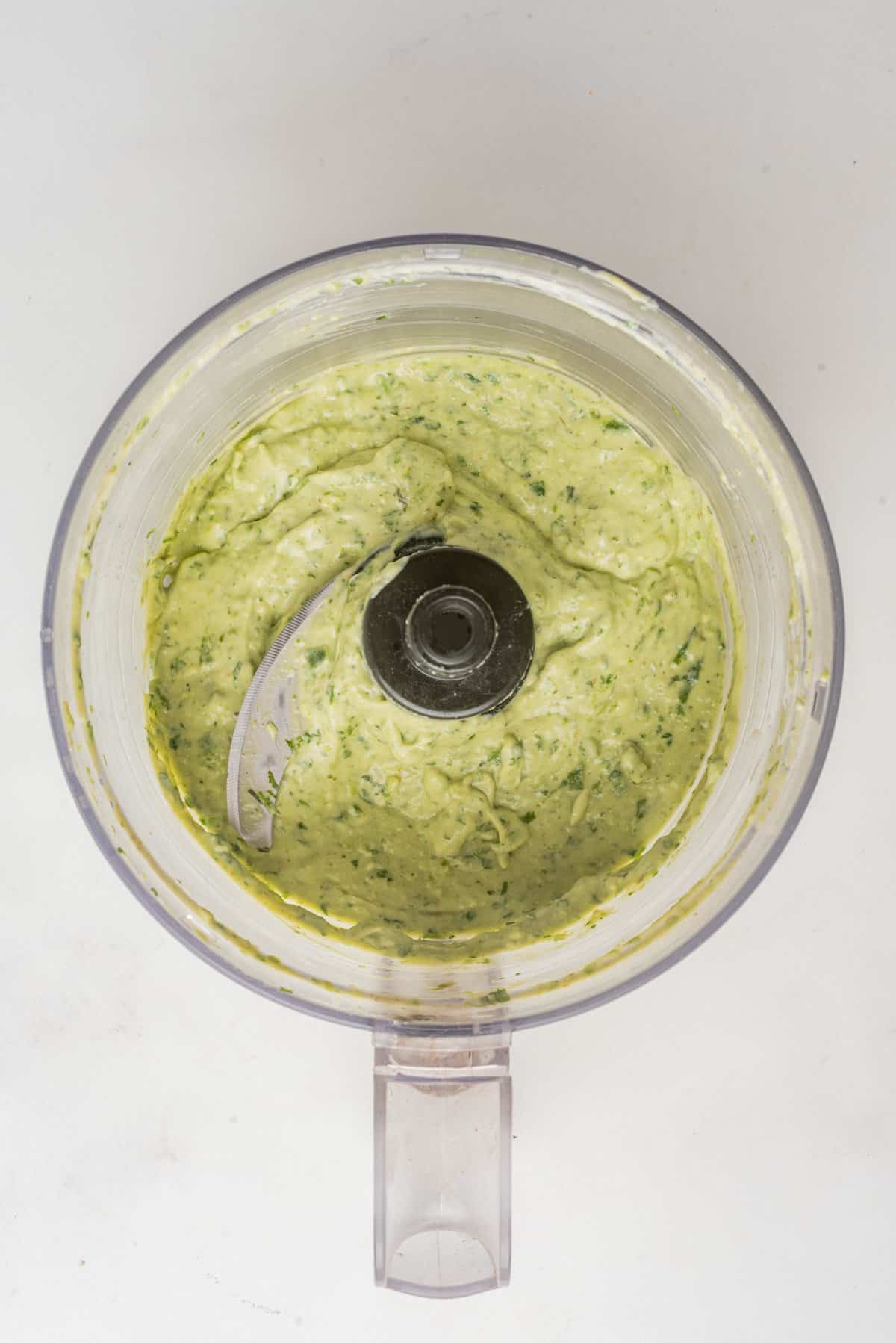 An overhead image of avocado cilantro lime dressing freshly blended in a blender.