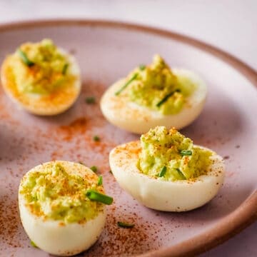 Close up square shot of avocado deviled egg on lilac plate.