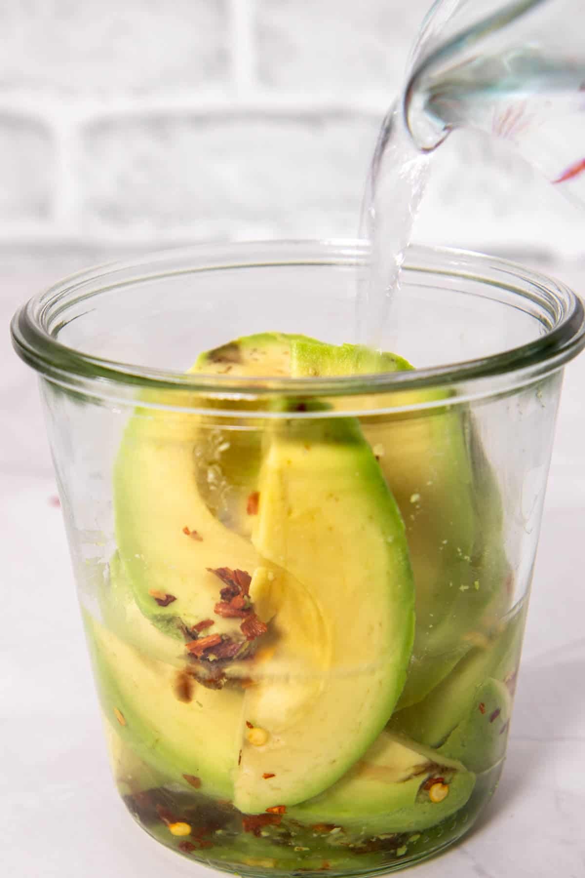 Pouring pickling liquid on avocados
