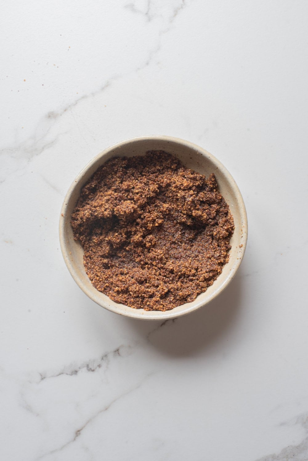 Olive oil and hot water added to ground mustard seeds and salt in a bowl.