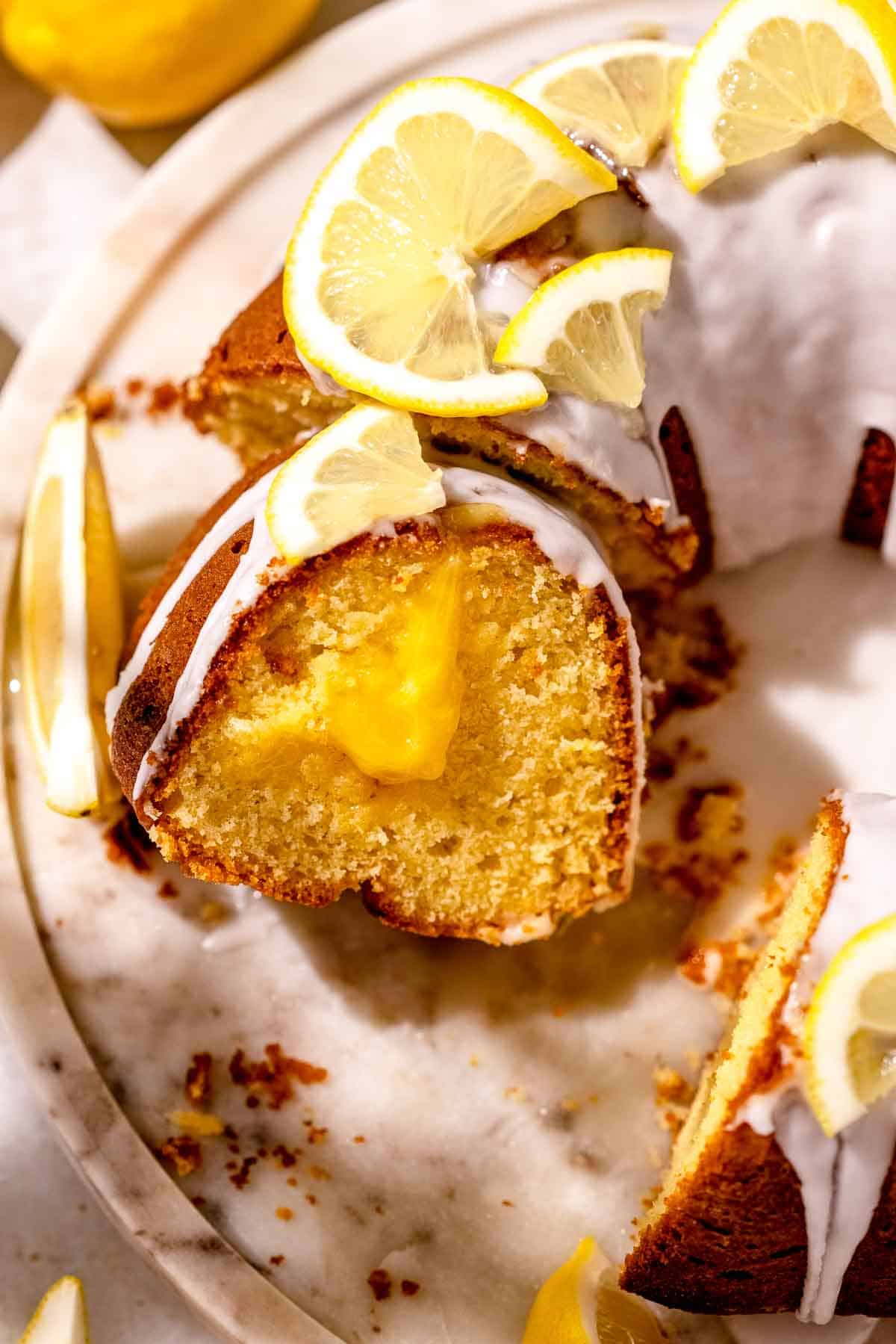 A close-up shot of sliced lemonade bundt cake with sliced lemons on top.