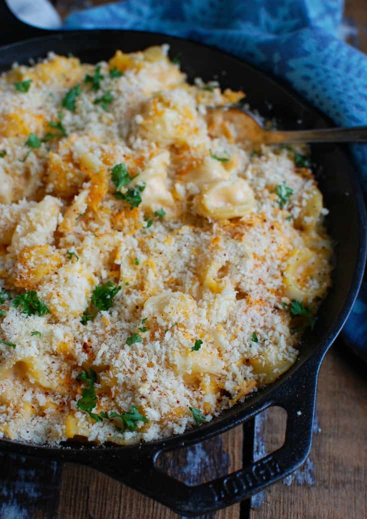 A straight shot of baked mac and cheese with bread crumbs on top and placed in a cast iron skillet.