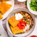 beans and cornbread served in a bowl with sour cream and tomatoes on top