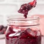 Close up of a spoonful of compote dripping back into the jar