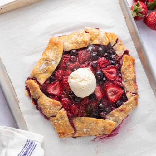 Baked berry galette in sheet pan with a scoop of icecream in the middle