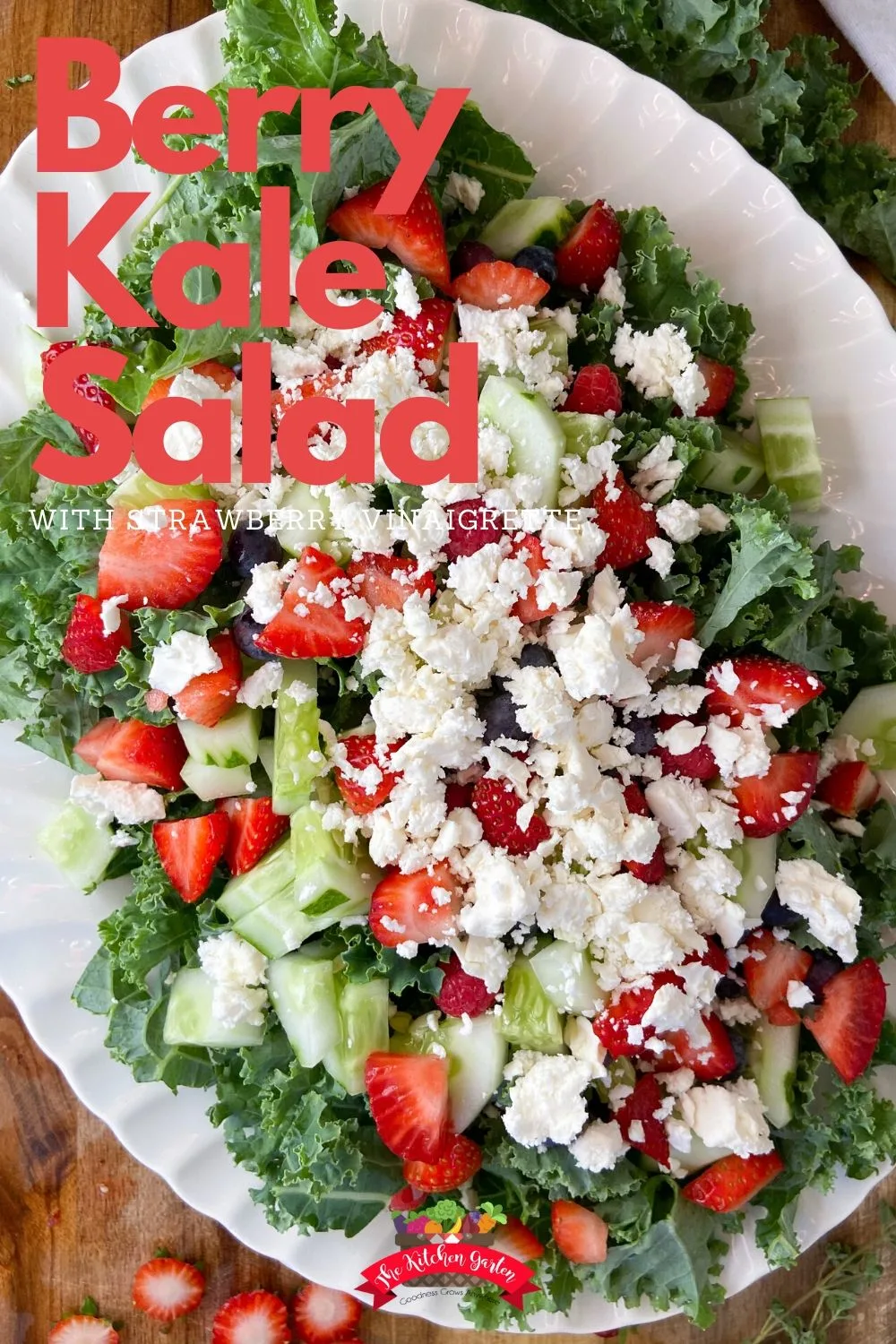 Overhead view of a berry kale salad with strawberry vinaigrette on a white plate. 