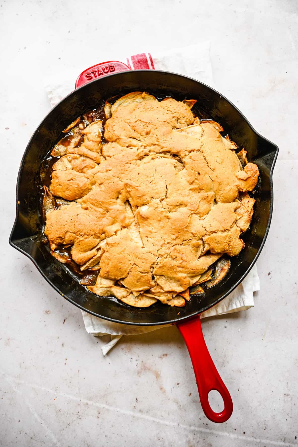 Overhead view of cooked Bisquick apple cobbler on a black cast-iron skillet pan.