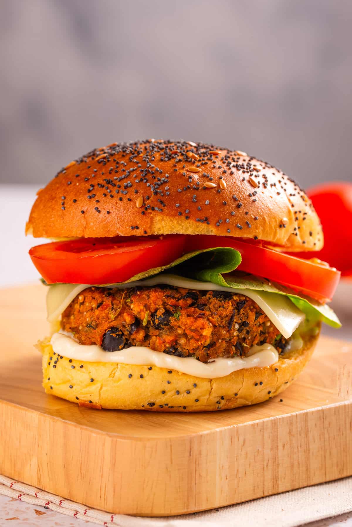A close up image of black bean quinoa burger with tomatoes and lettuce on a cutting board.