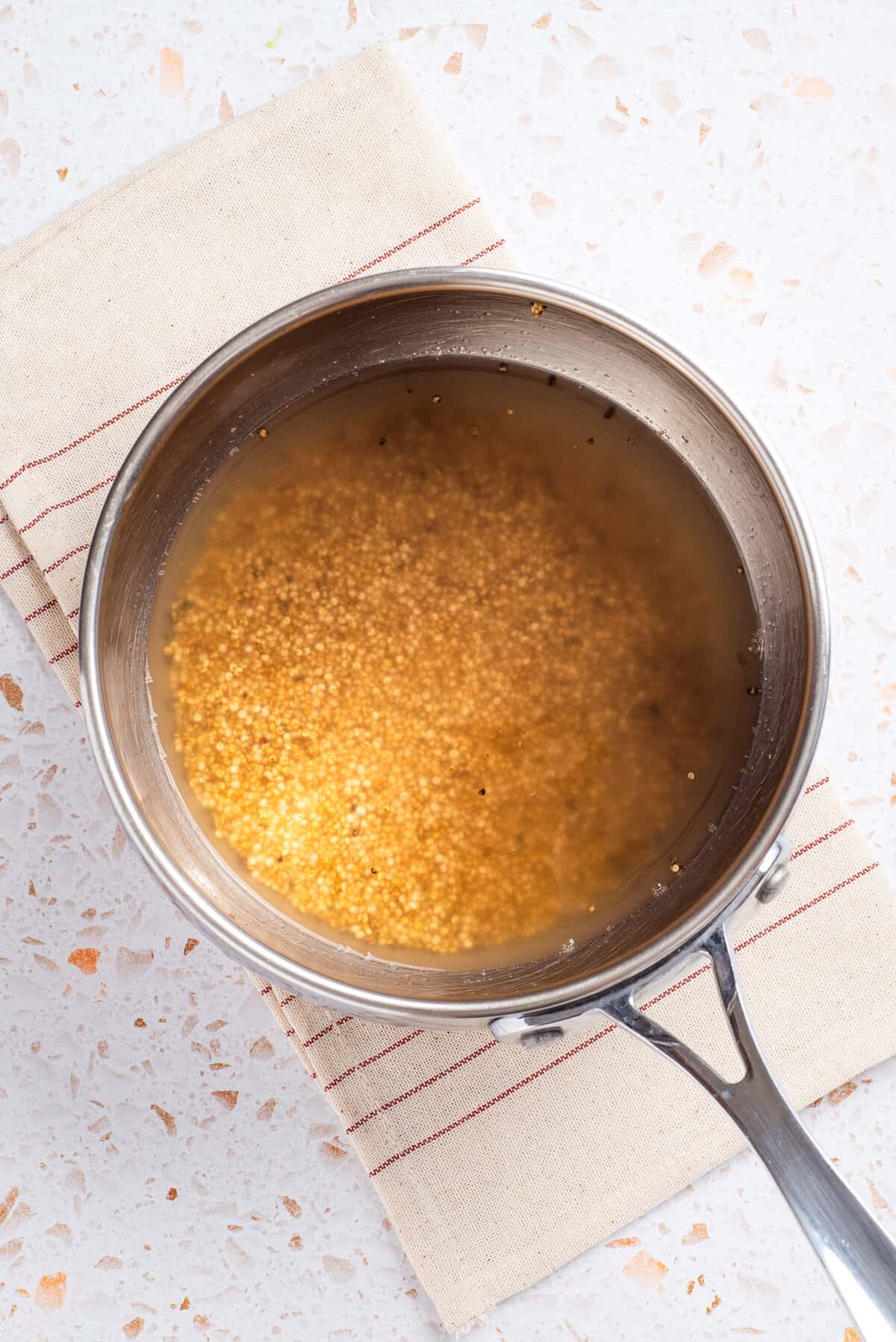 An overhead image of quinoa and water in a saucepan.
