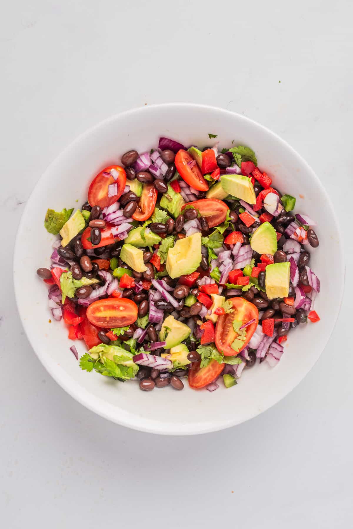 An overhead image of black bean salad gently tossed until combined together.