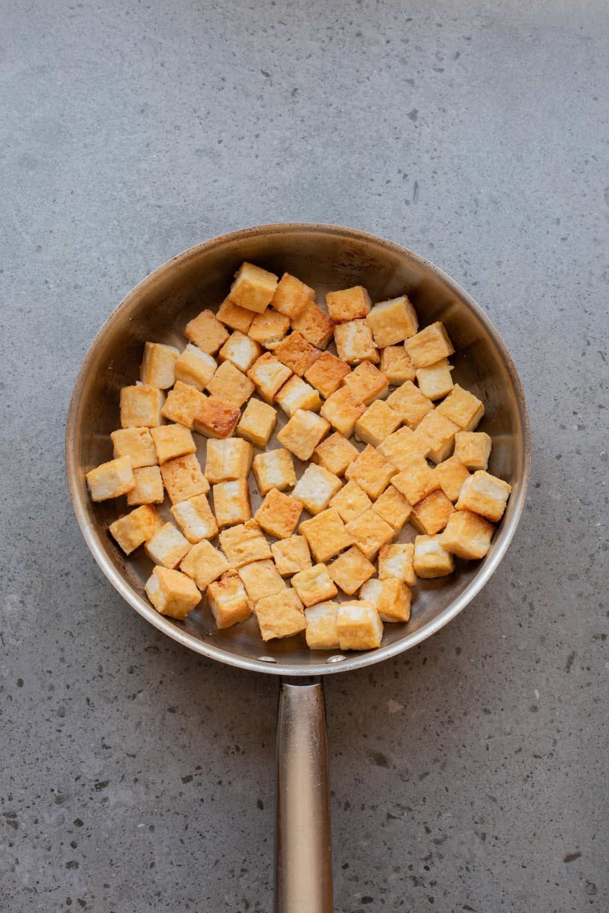 An overhead image frying the tofu until crispy.