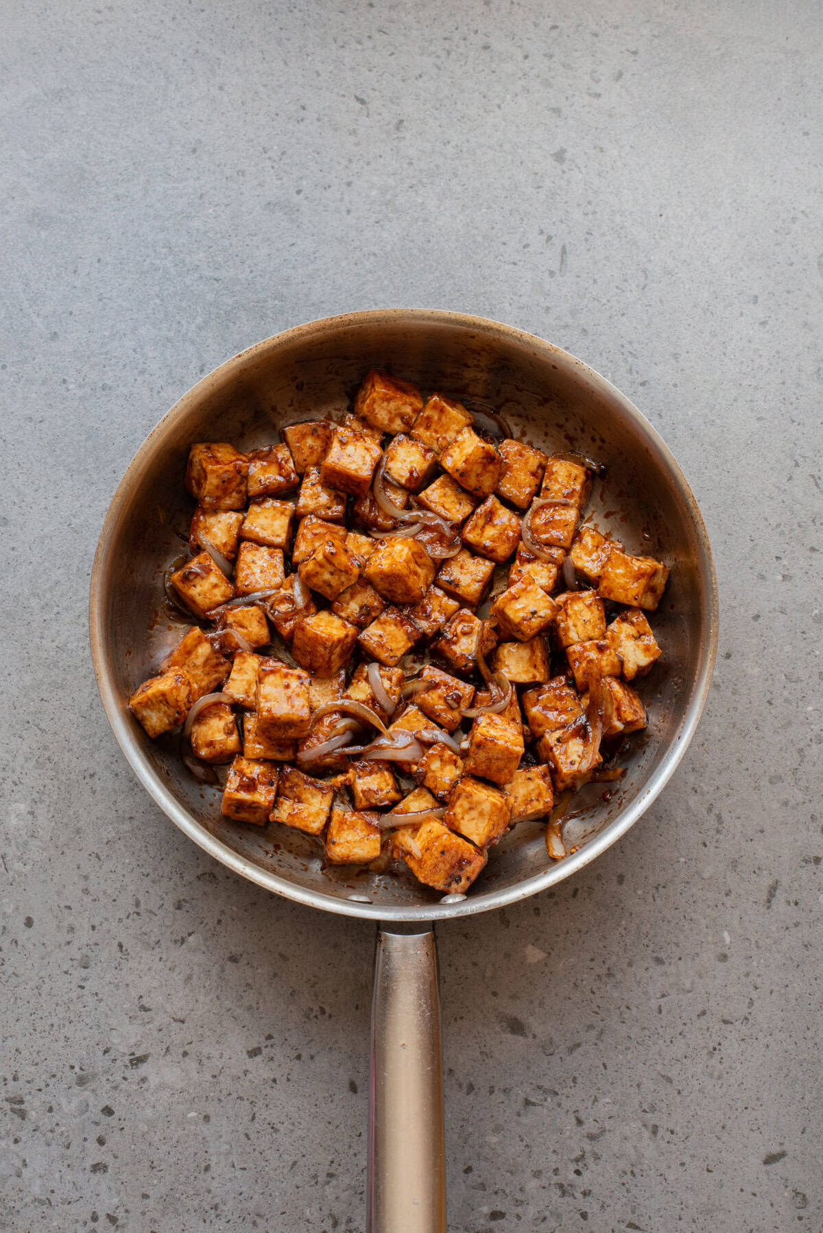 An overhead image of coating the tofu with the sauce in the skillet.
