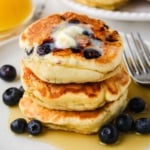 A close up image of blueberry cottage cheese pancakes stacked on a plate.