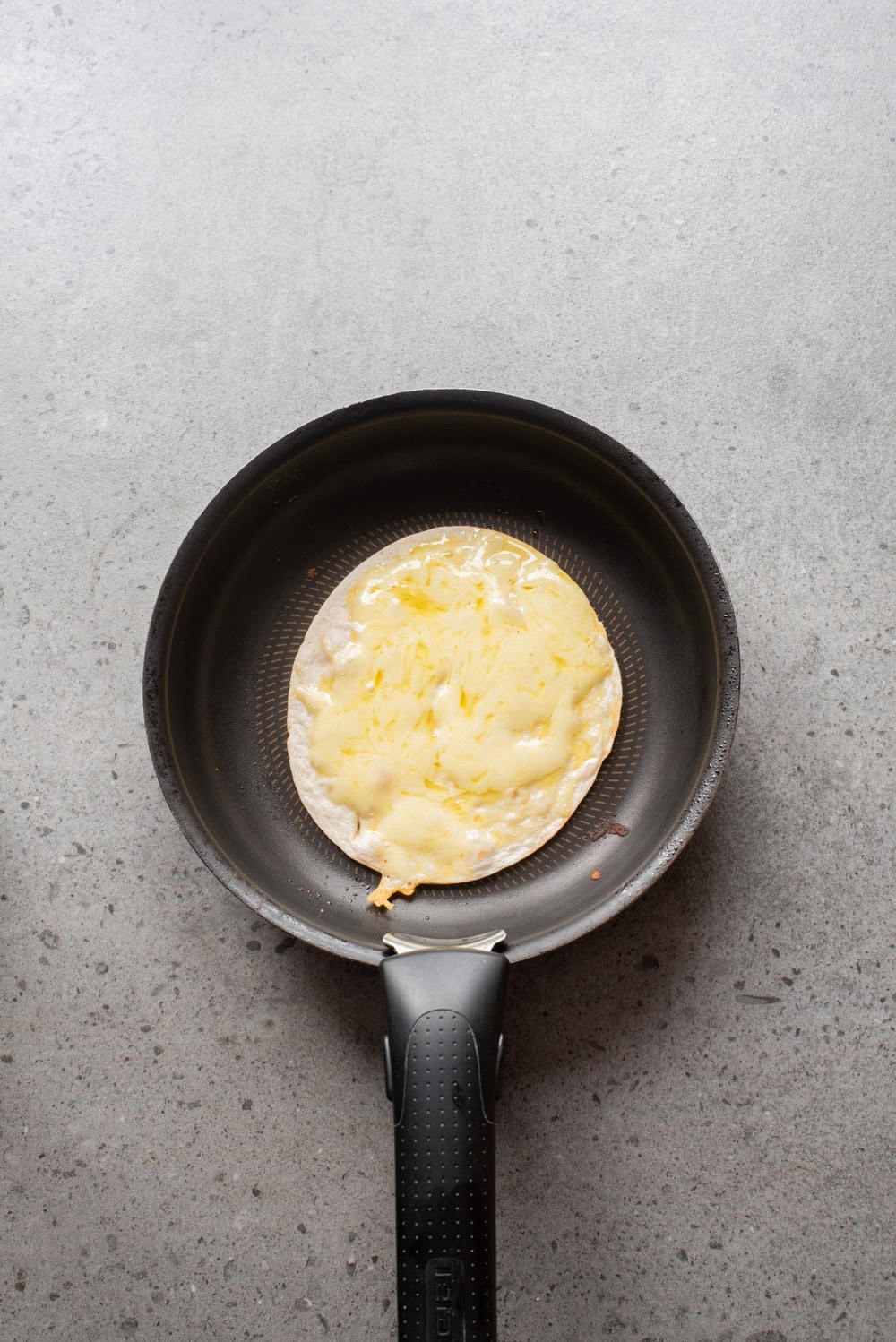 An overhead image of toasting the flour tortilla on a pan.