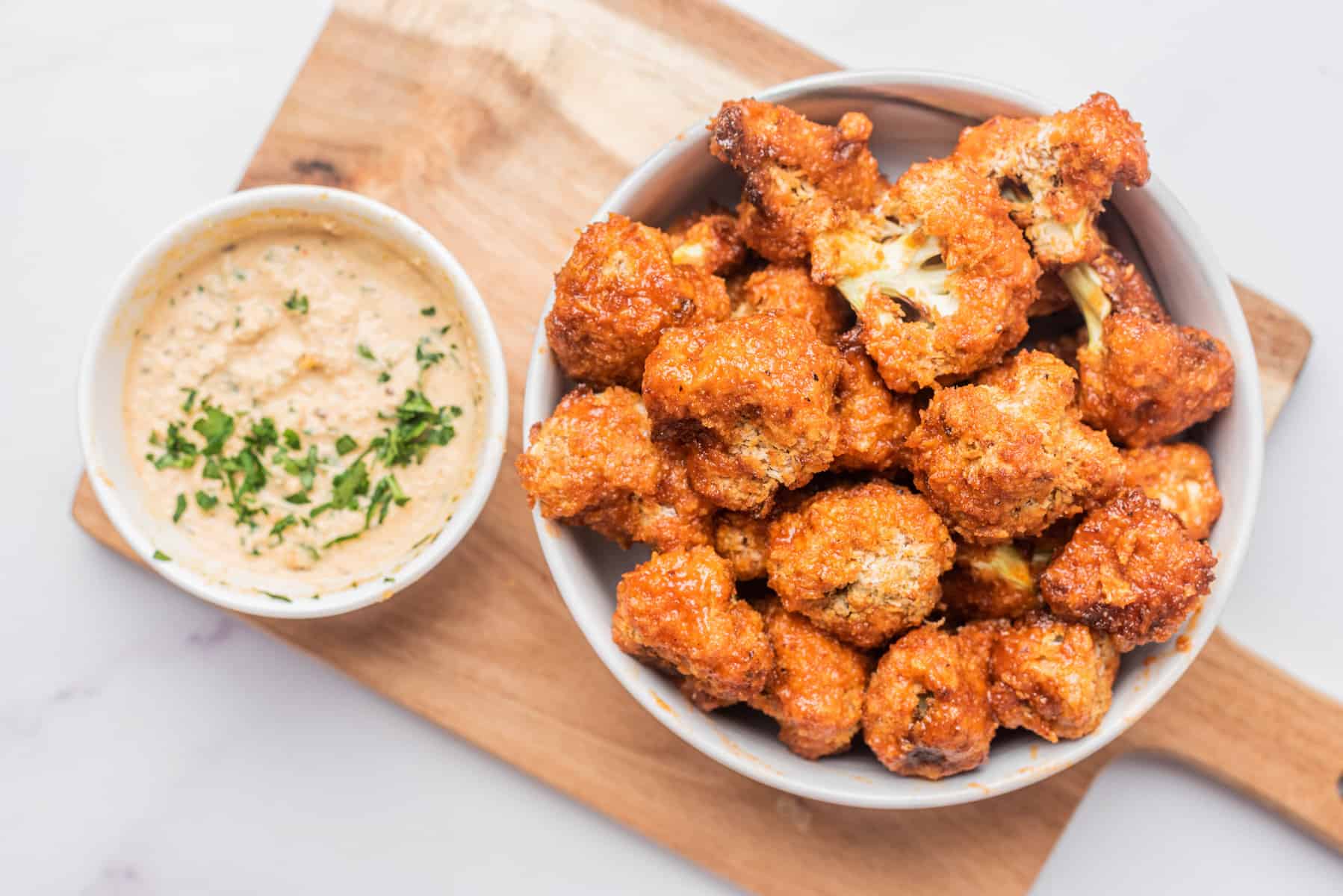Horizontal photo of air fryer buffalo cauliflower with a dipping sauce on the side. 