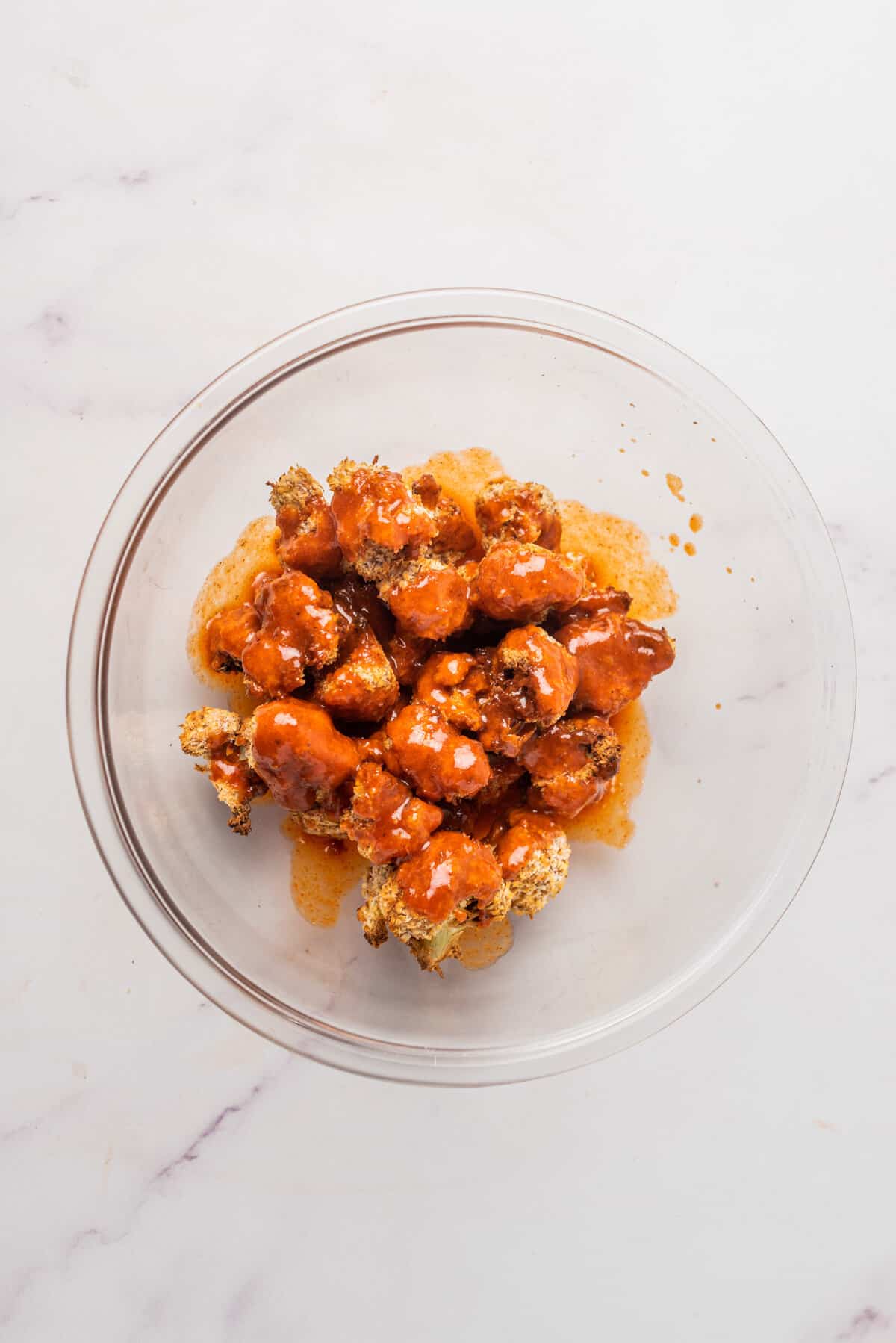 An image of air fryer vegan cauliflower bites in a bowl, covered with buffalo sauce