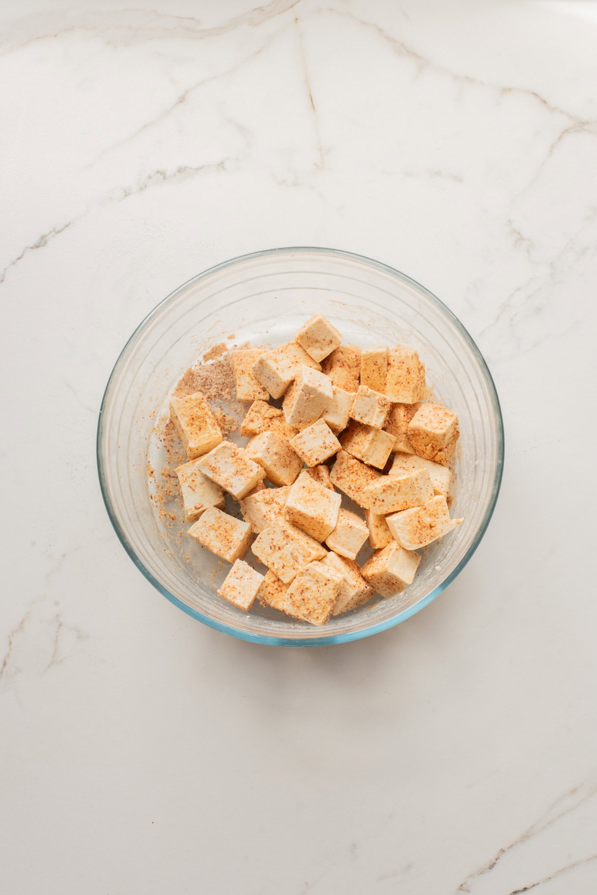 An overhead image of seasoning tofu in a bowl.