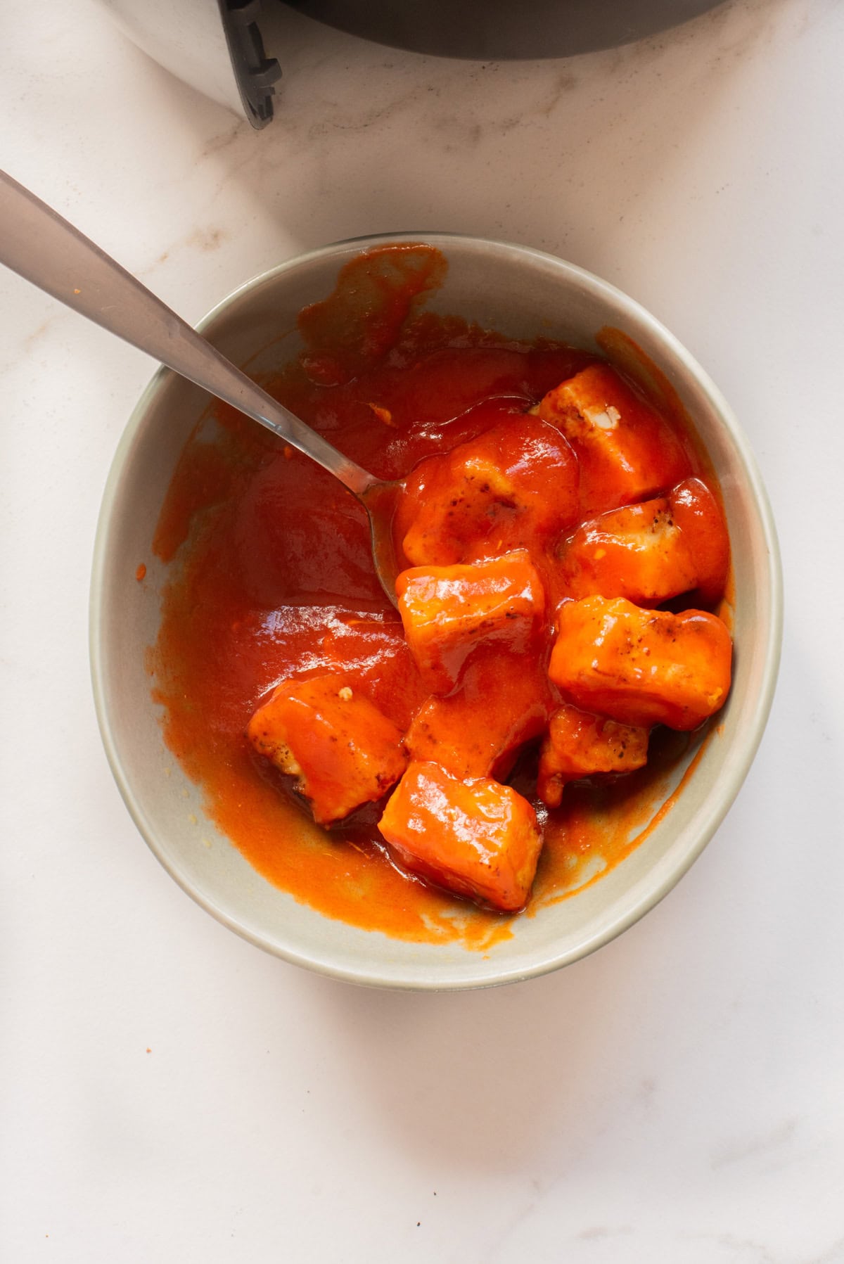 An overhead image of tossing tofu in buffalo sauce.
