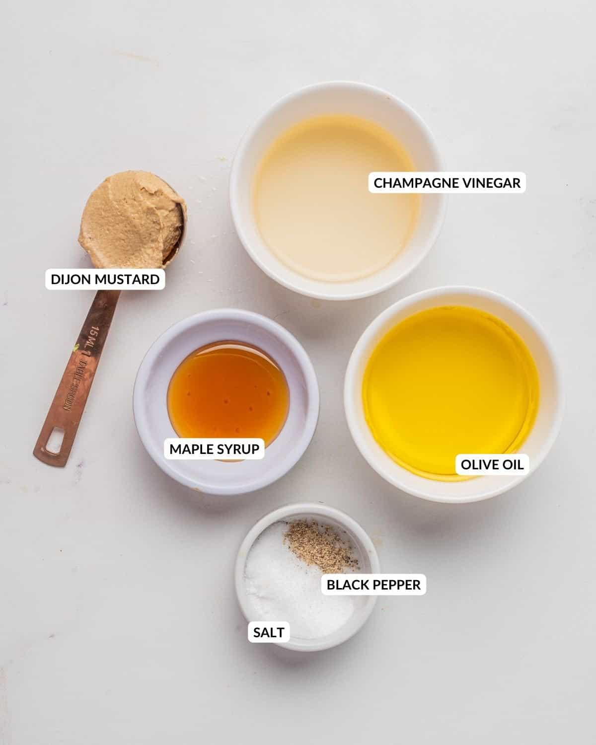 An overhead image of champagne vinaigrette ingredients in separate bowls with a label for each ingredient.