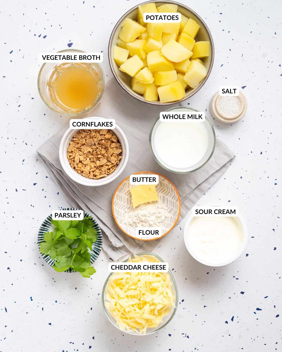 An overhead image of the ingredients of cheesy potatoes with labels on each of them.