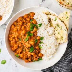 An overhead image of chickpea tikka masala served on a plate with rice and naan.