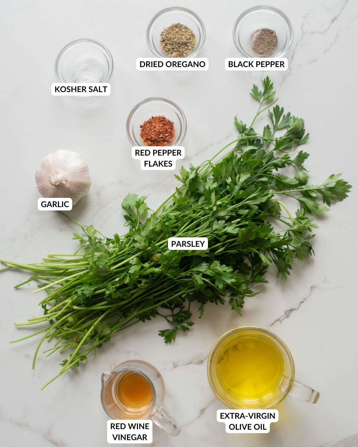 Ingredients for classic chimichurri sauce on a marble surface.
