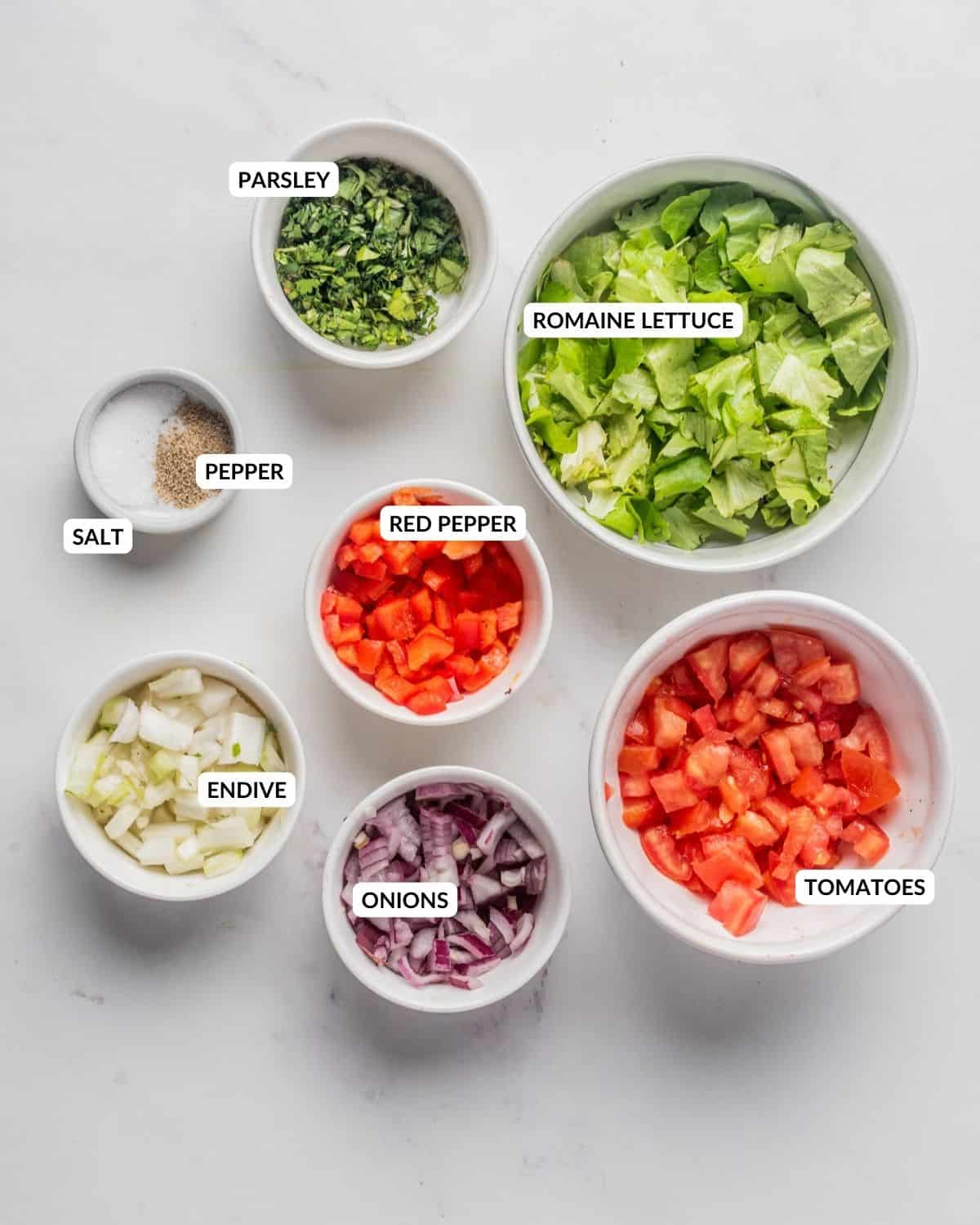 An overhead image of the ingredients of chopped salad in separate bowls with a label.